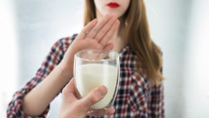 woman stopping a glass of milk given to her -Lactose Intolerance