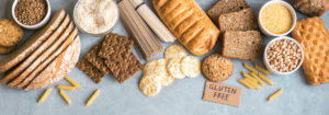 Various gluten free pasta, bread, snacks and flour on light gray background, top view, banner - celiac disease