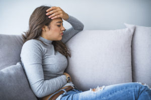 woman sitting a couch having a stomach ache