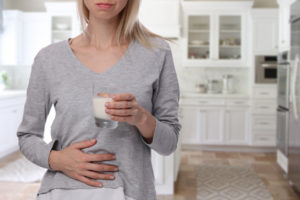 Woman with stomach pain after drinking a glass of milk