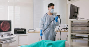 asian male doctor wearing protective gown is doing colono cancer sceening test