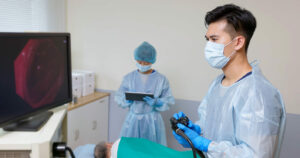 Colonoscopy endoscopic examination performed by two male doctors.