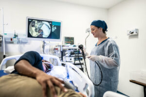 A gastroenterologist is doing an endoscopy on the patient in the hospital room.