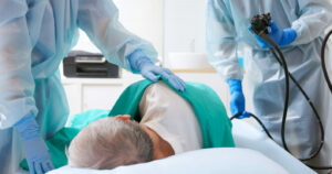 An image depicting a colonoscopy (colon cancer screening) being performed on an elderly patient.