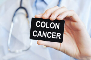 A gastroenterologist is holding a paper card that says Colon Cancer.