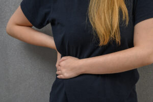 A young lady is holding her stomach due to pain from gallstone formation.