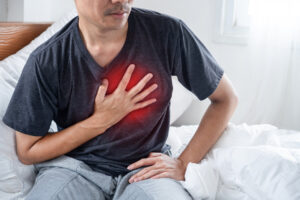 A man grips his chest, showing visible discomfort from heartburn.